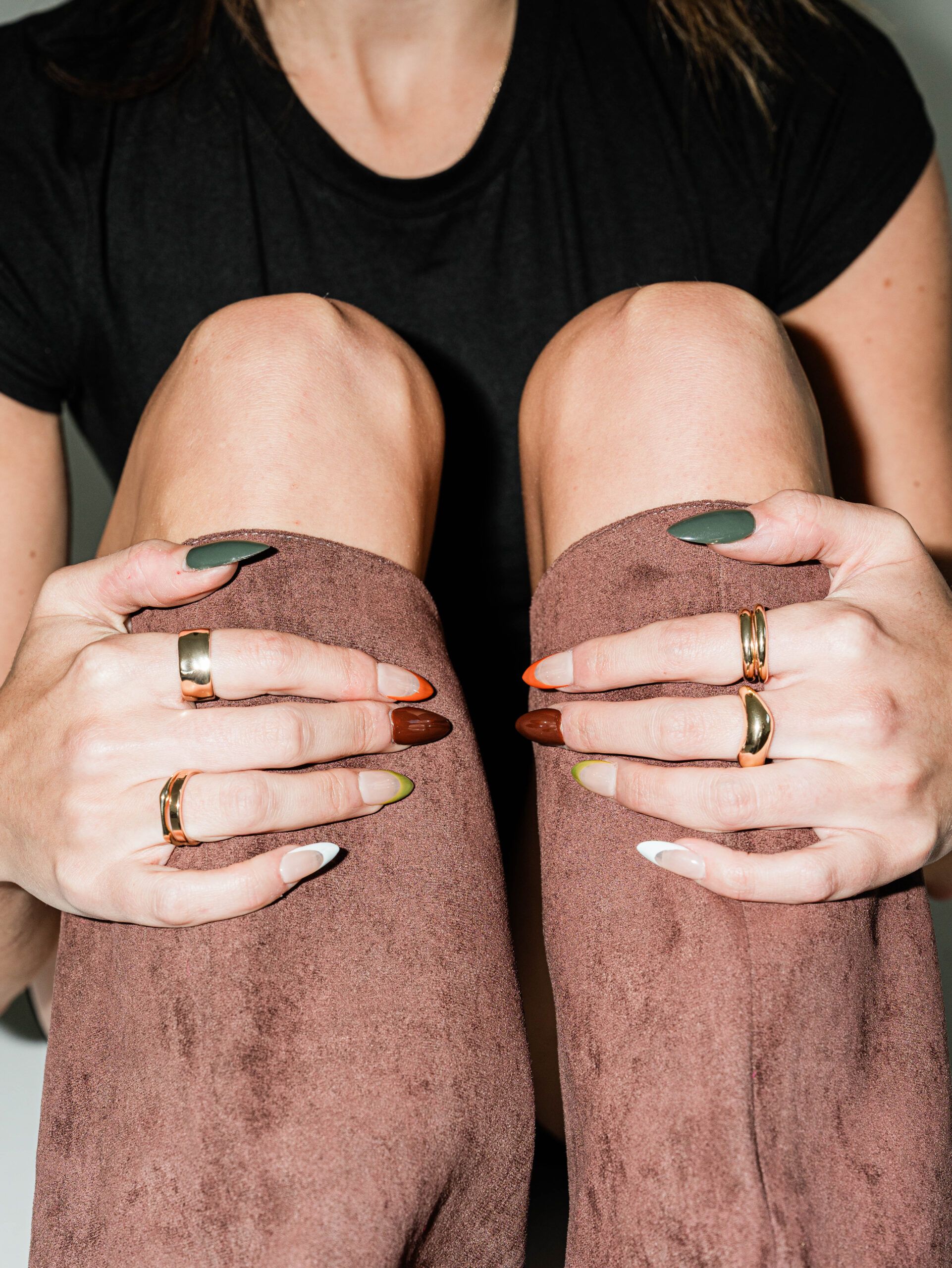 Seated woman holding her feet and showing elevated nail art at a Columbus nail studio